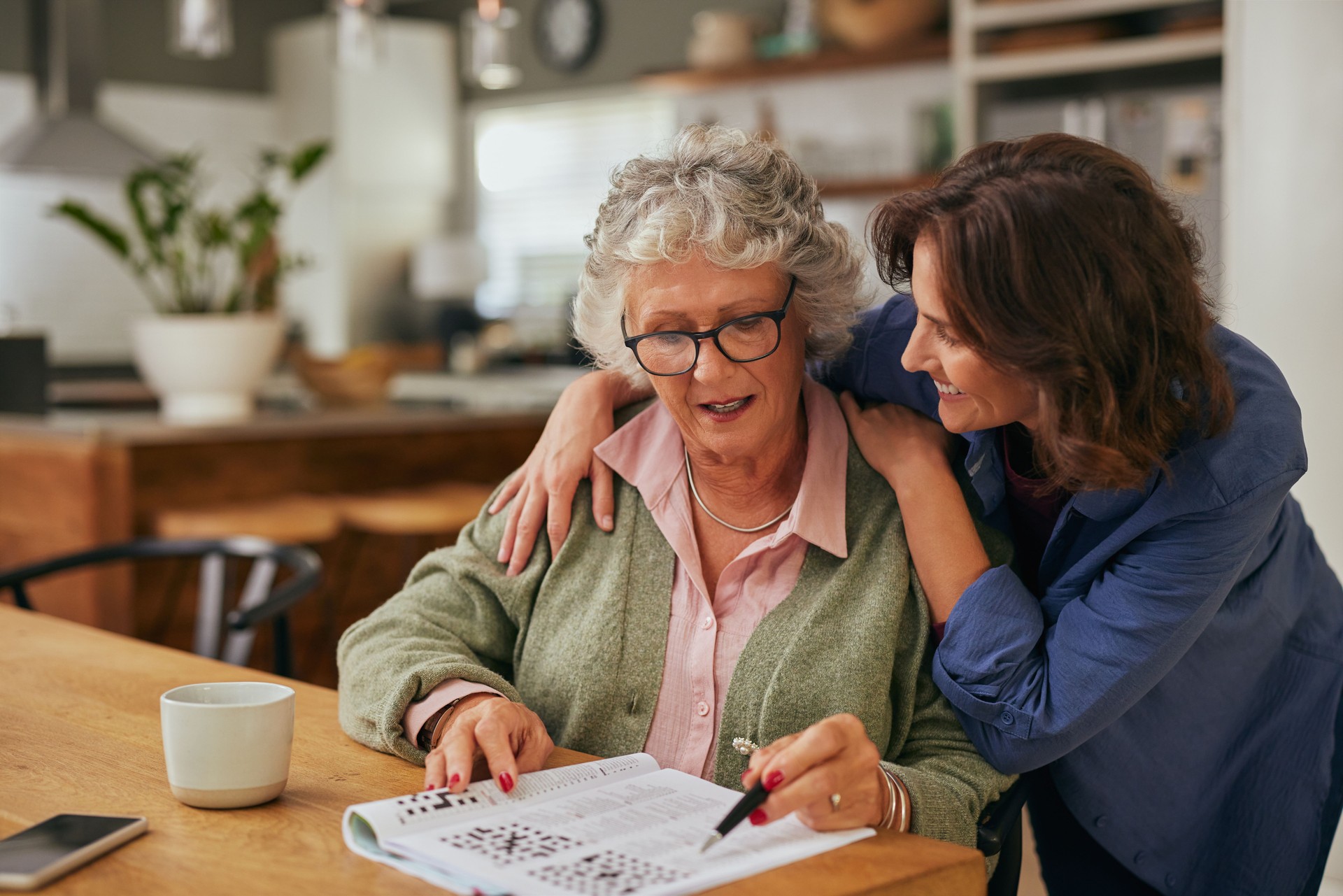 Senior woman solving crossword puzzle with the help of her daughter
