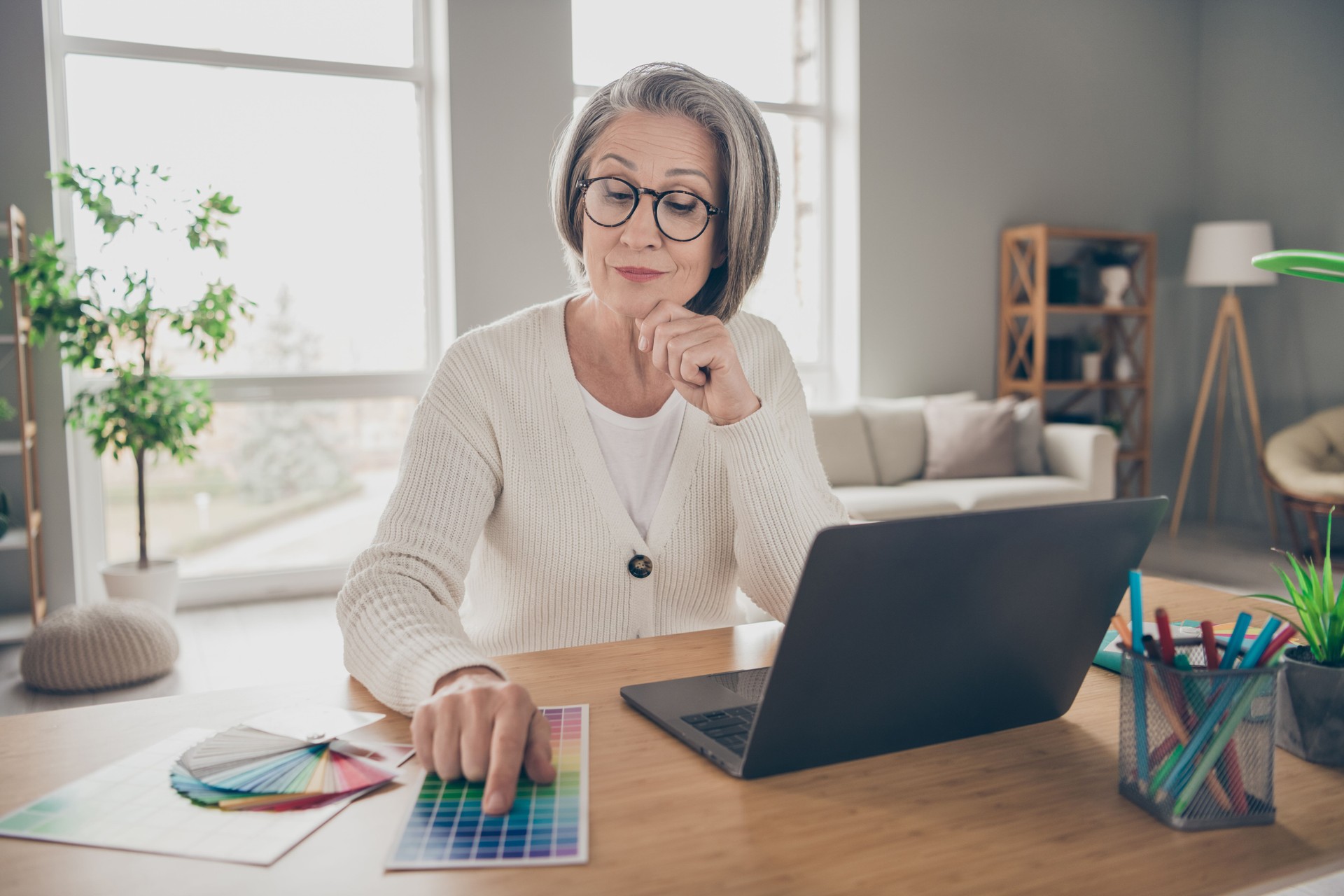 Photo of good mood thoughtful elderly lady designer wear white cardigan choosing architect colors indoors apartment room